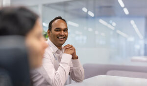 Man with folded hands smiles at camera